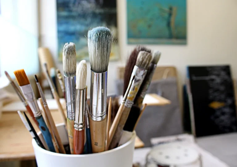 Paint brushes stored in a white container in artist studio