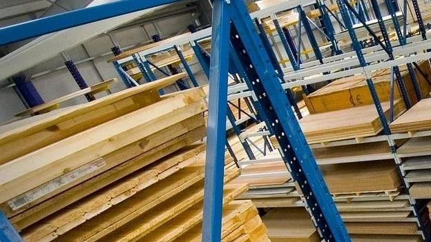 Sheets of plywood stacked on blue warehouse racking