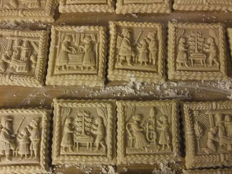 Pressed springerle cookies with raised scenes resting on a floured wooden board