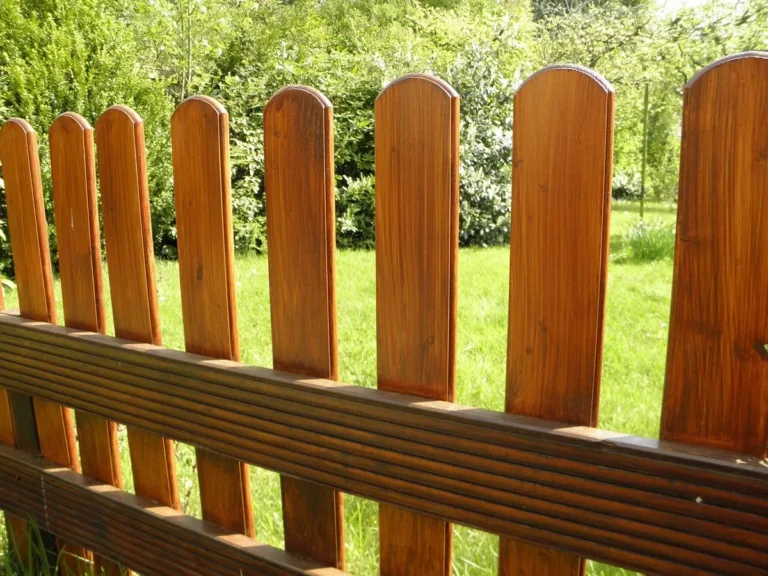 Freshly sealed wooden picket fence with warm cedar-tone finish