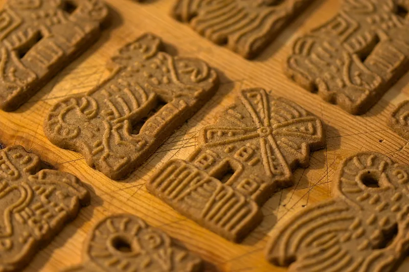 Speculaas cookies with windmill and animal designs on a wooden board