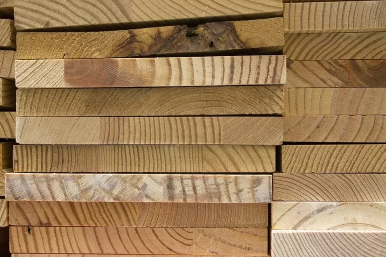 Stack of rough-sawn hardwood lumber boards showing end grain and growth rings