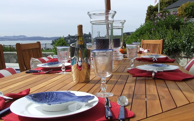 Honey-brown teak outdoor dining table set for a meal Honey-brown teak outdoor dining table set for a meal