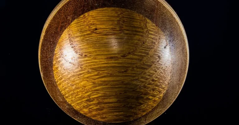 Turned wooden bowl with a warm amber glossy finish on a black background