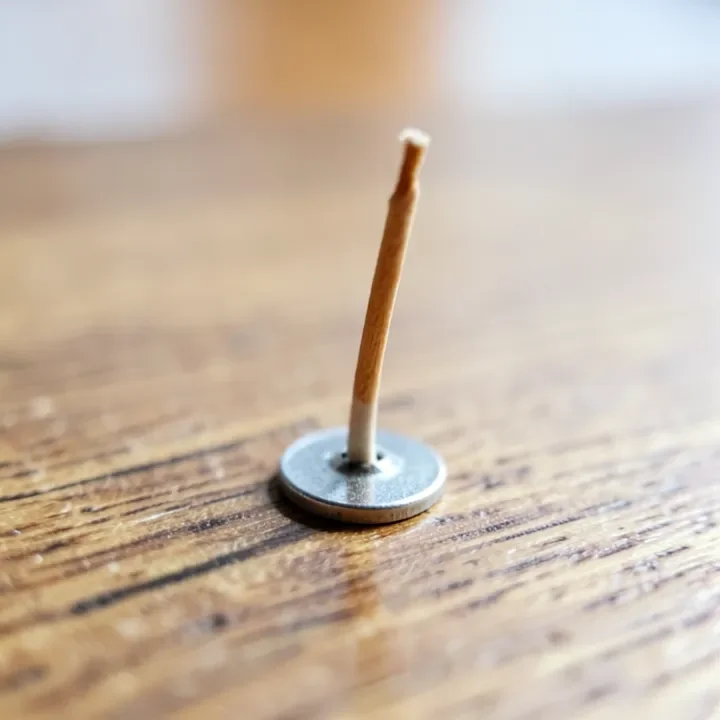 A wood wick clipped into its metal base before being placed in a candle jar
