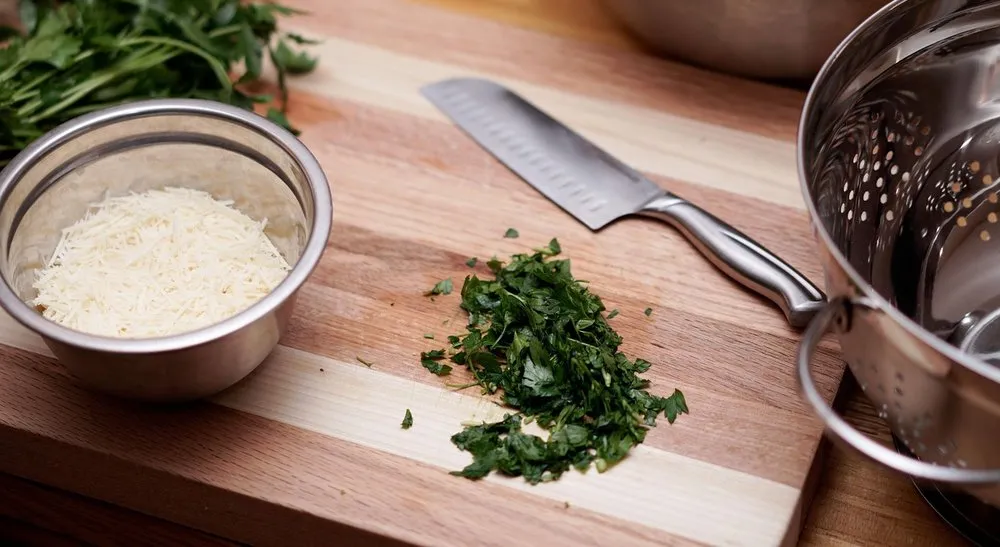 Striped wooden cutting board with a chef knife and chopped parsley