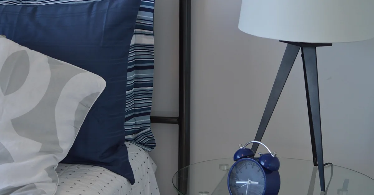 Cozy bedroom nightstand with lamp and alarm clock, a peaceful sleep environment