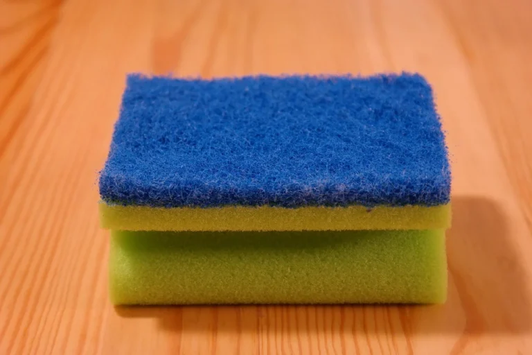 Hand with cleaning sponge removing stain from fabric