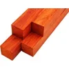 Four kiln-dried padauk turning blanks stacked, showing bright reddish orange color