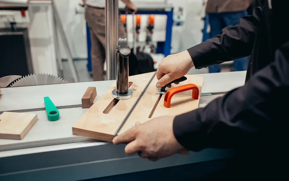 A woodworker adjusting a shop-made jig and fence guide on a table saw bench