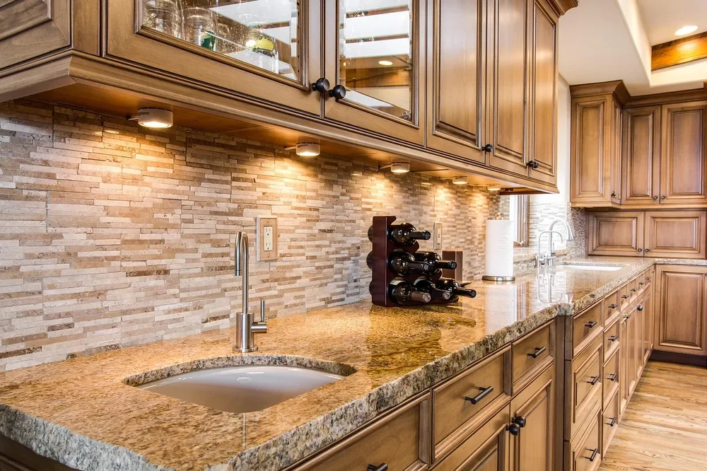 Stained hardwood kitchen cabinets with under-cabinet lighting and granite counters