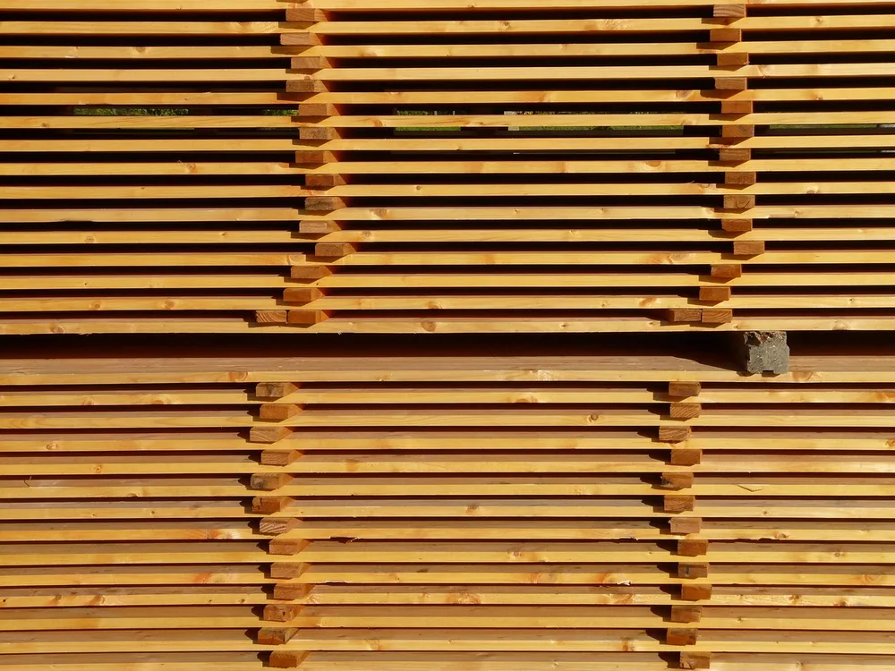 Stacked boards separated by spacer sticks so air can circulate while lumber dries