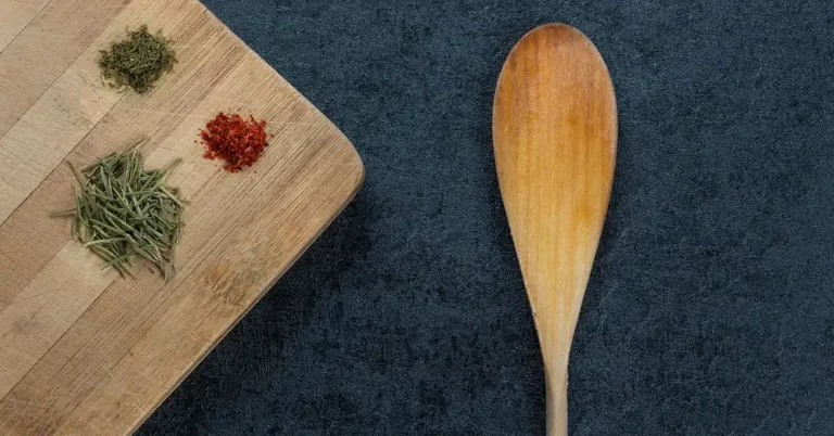 Wooden cutting board and spoon on a dark surface