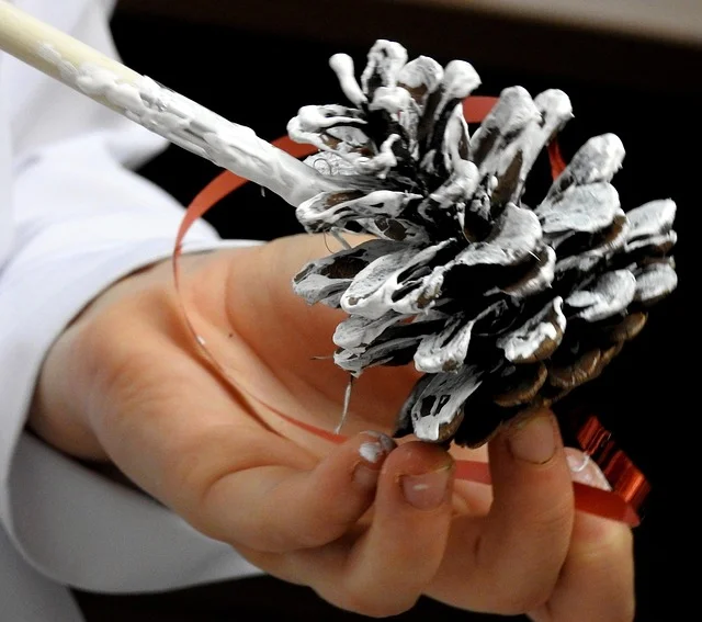 Hand painting a real pine cone white with acrylic paint using a brush