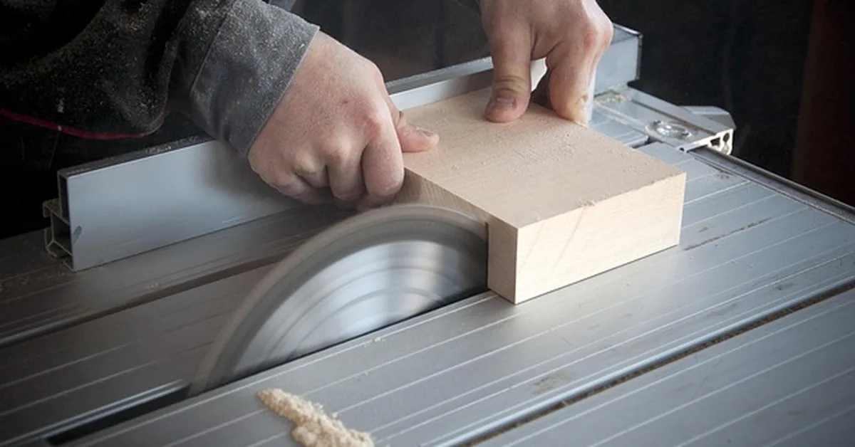Hands guiding a wood block through a table saw blade — comparing electric wood-cutting tools for DIY projects