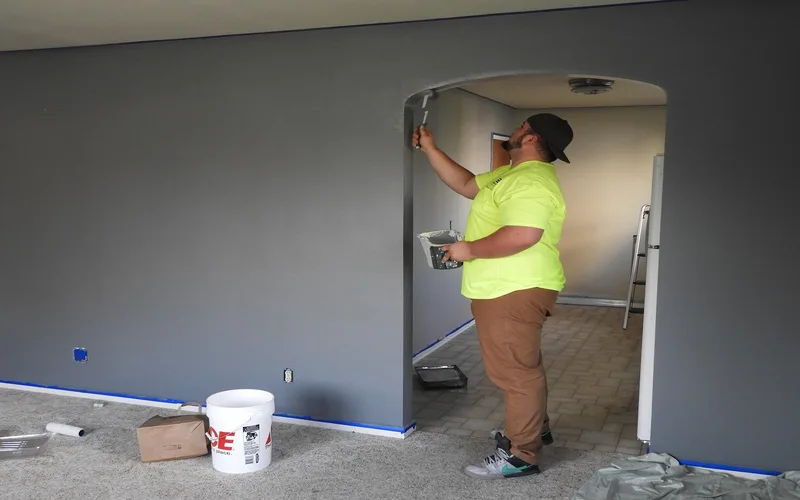 Painter rolling indoor latex paint onto an interior living room wall
