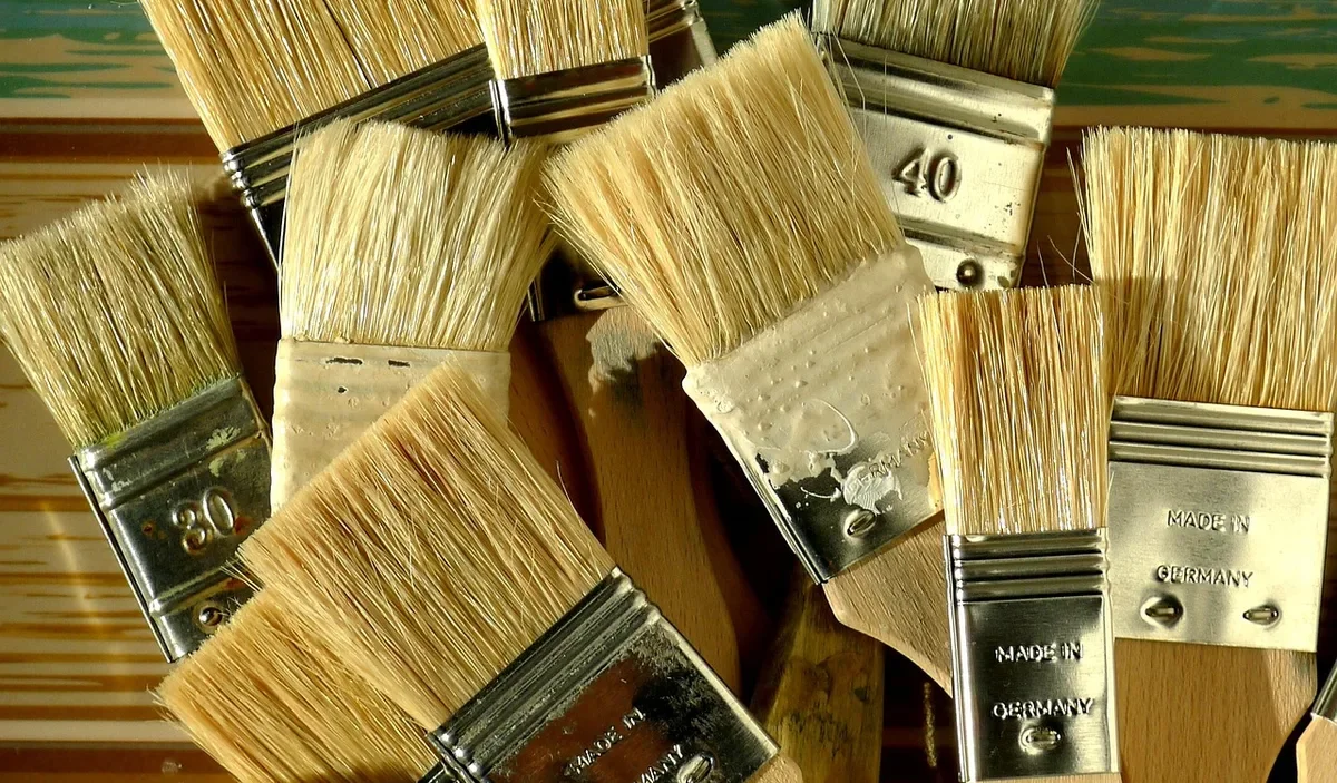Pile of natural bristle paint brushes with metal ferrules and wooden handles