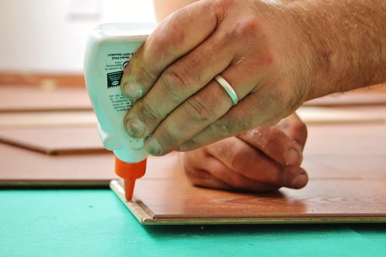 Hands applying wood glue to wood in woodworking project