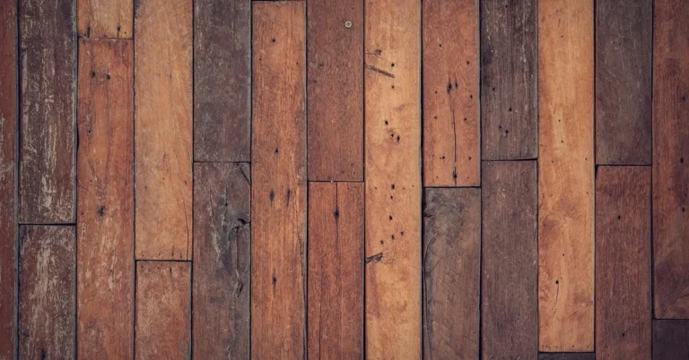 Worn hardwood floor planks showing scuffs, scratches and nail holes