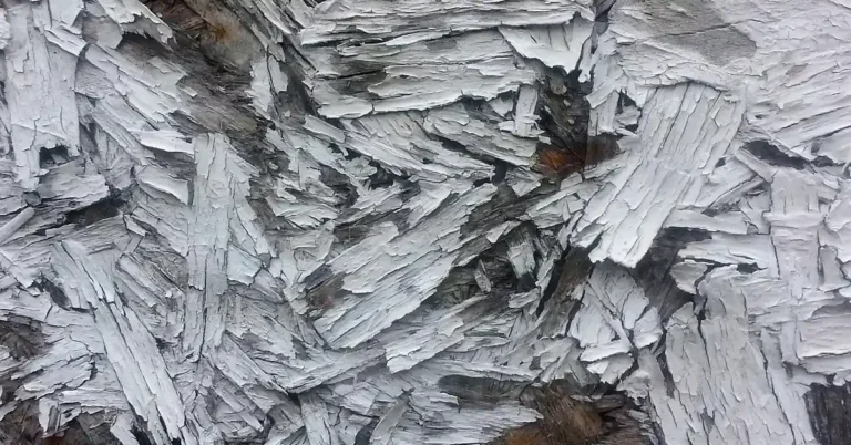 Close-up of OSB strands with white paint flaking off the rough surface