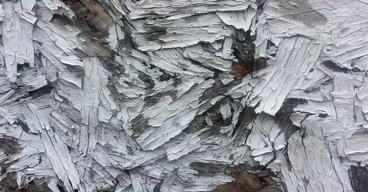 Close-up of OSB strands with white paint flaking off the rough surface