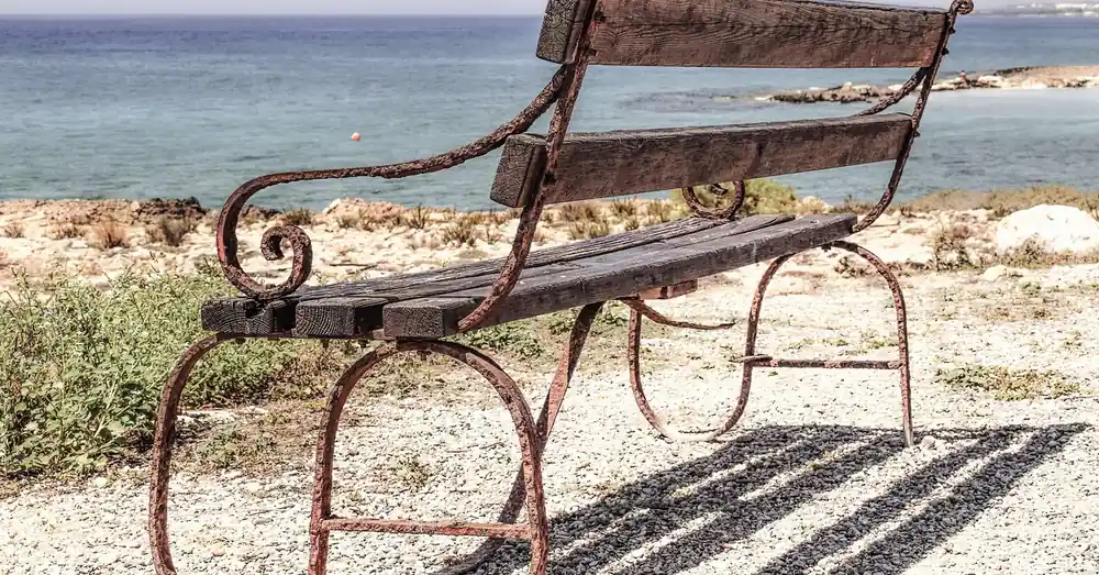 Rusty wrought iron bench frame with weathered slats outdoors
