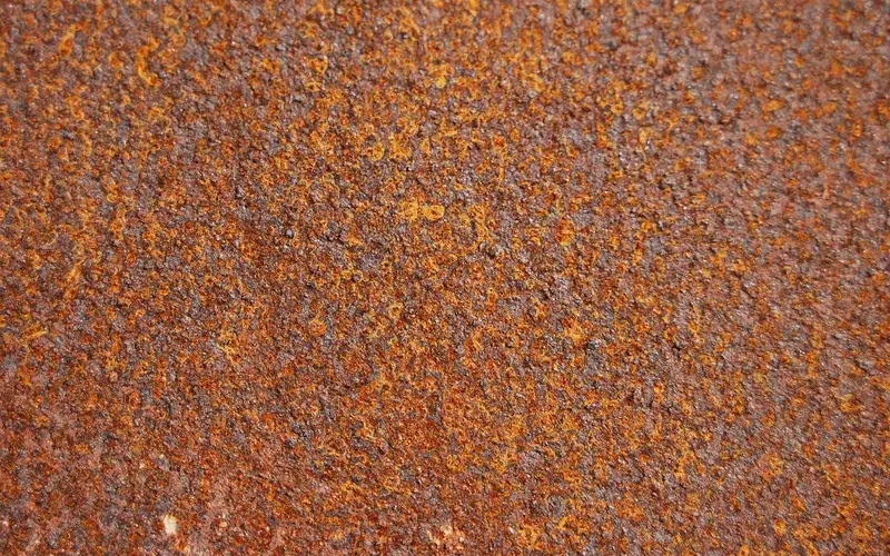 Close-up of a rusty metal surface showing flaky reddish-brown corrosion