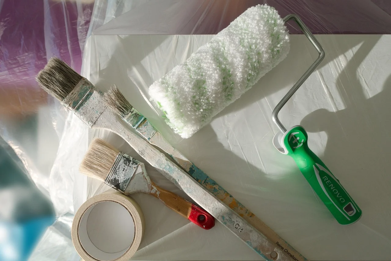 paintbrushes, foam roller, and painters tape staged for priming a fiberglass door