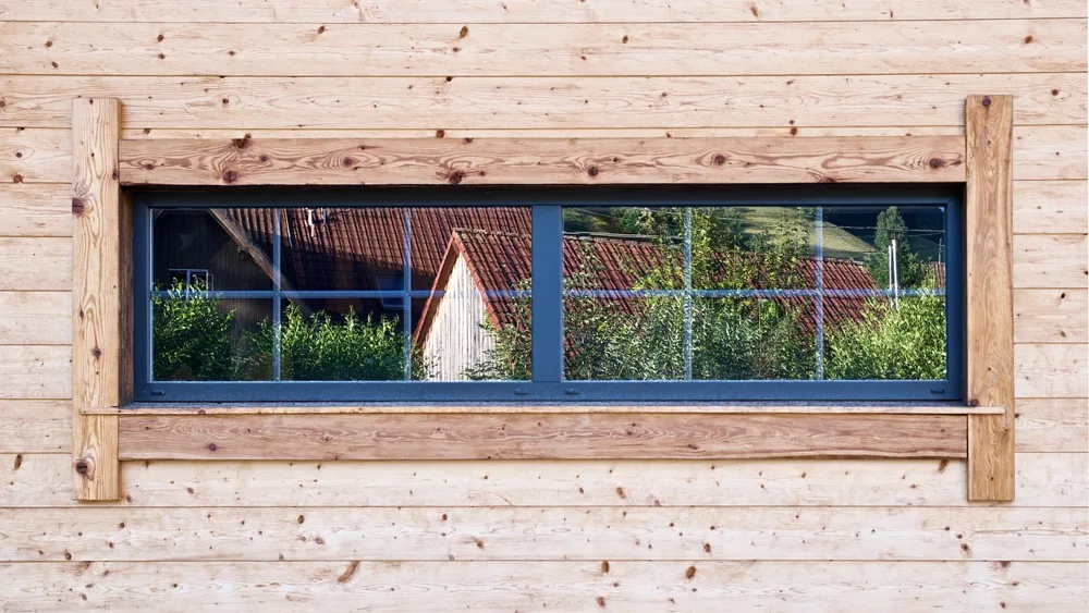 Knotty softwood exterior wall cladding with a light clear finish around a window