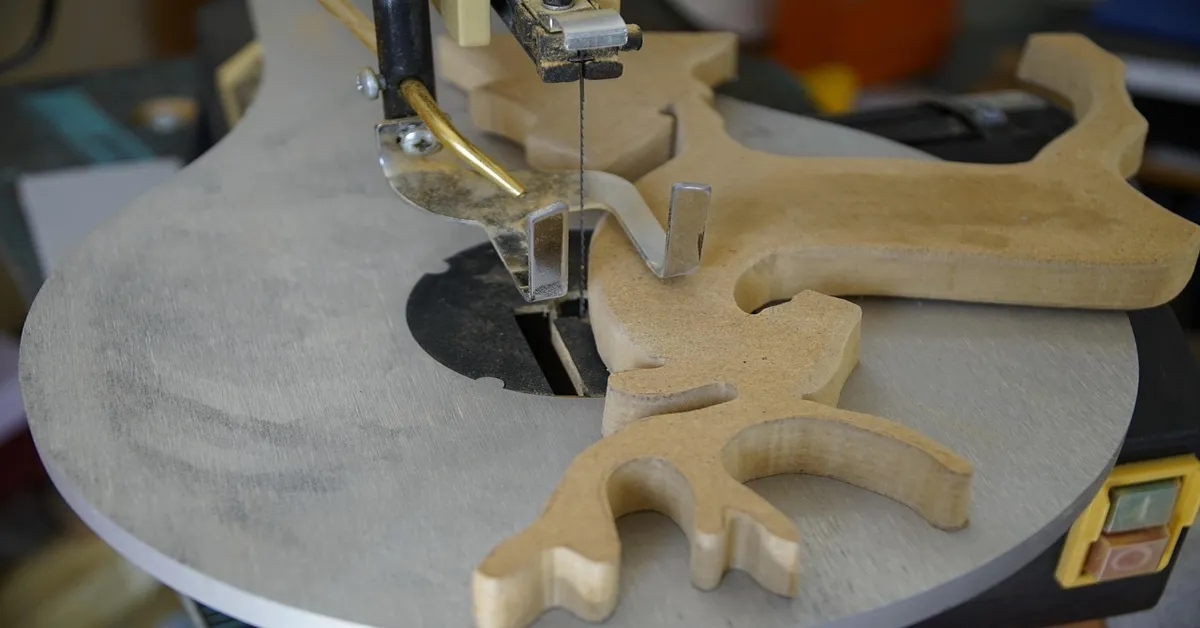 Scroll saw cutting detailed wood pattern in a workshop