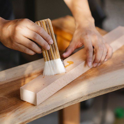 Brushing tung oil finish onto a piece of wood