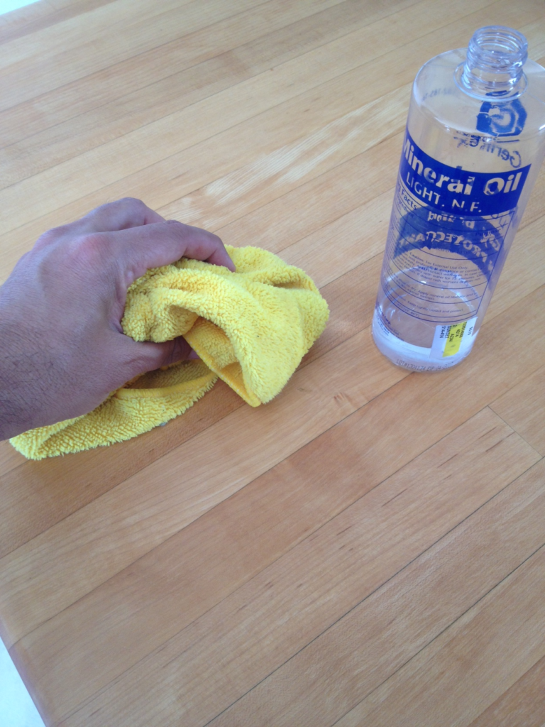Applying food-safe mineral oil to a hardwood countertop surface with a cloth