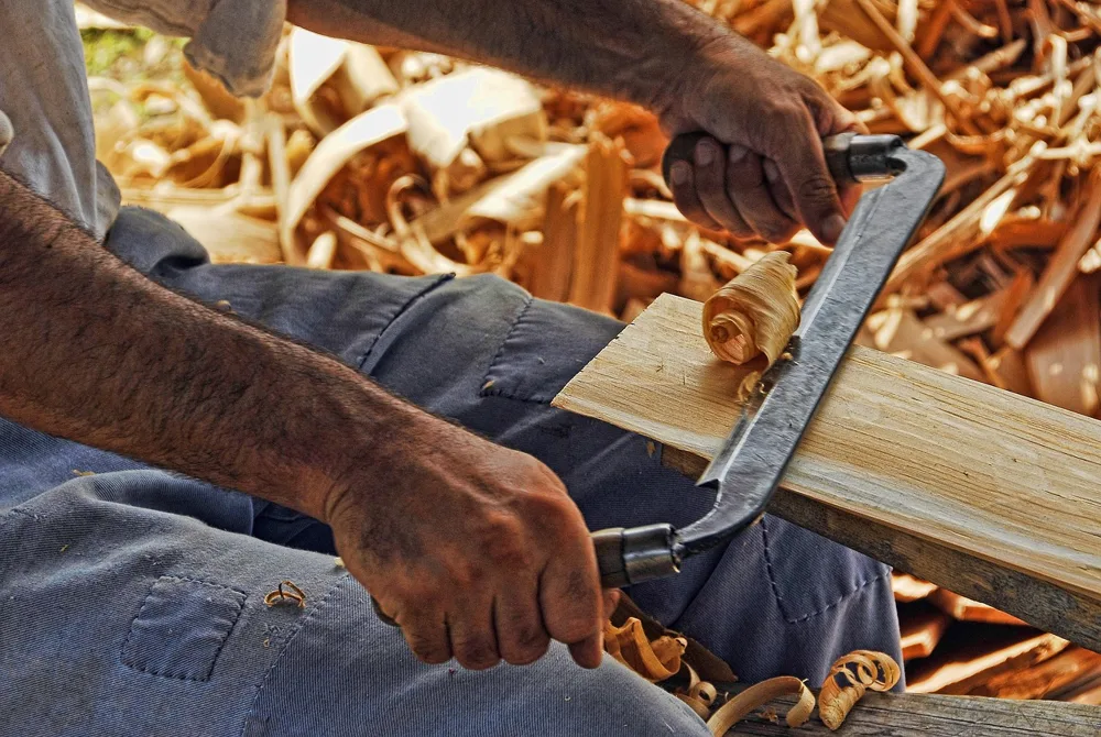 Hand plane shaving a wood board, similar technique used for planing MDF