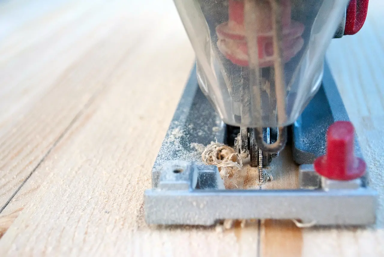 Woodworking jigsaw cutting a board, close-up on blade and baseplate Woodworking jigsaw blade cutting into a wood board, close-up on the baseplate and sawdust