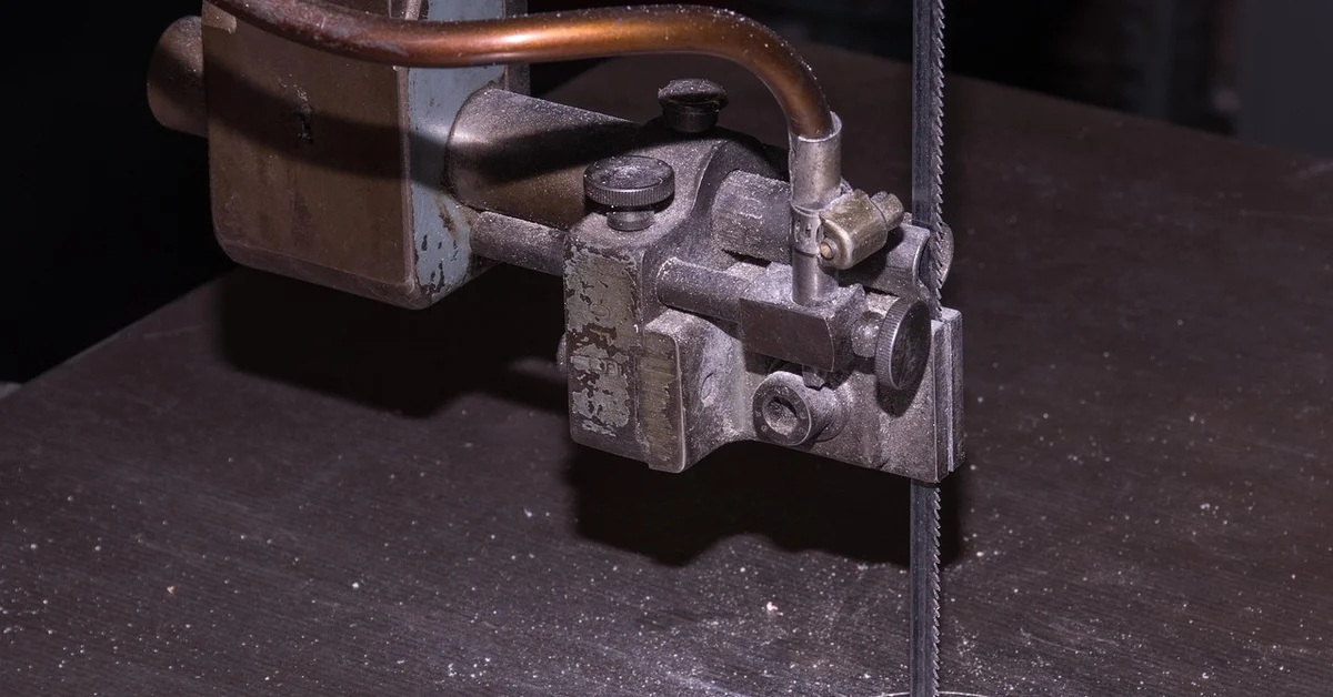 A metal-cutting band saw blade guide assembly with coolant line, typical of a metal-cutting bandsaw setup A metal-cutting band saw blade guide assembly with coolant line, typical of a metal-cutting bandsaw setup