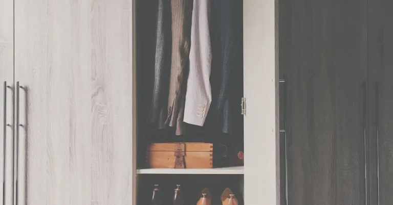 Open closet with wood shelves holding shoes below hanging clothes