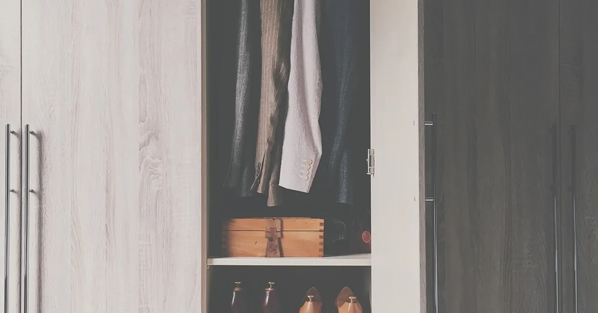 Open closet with wood shelves holding shoes below hanging clothes