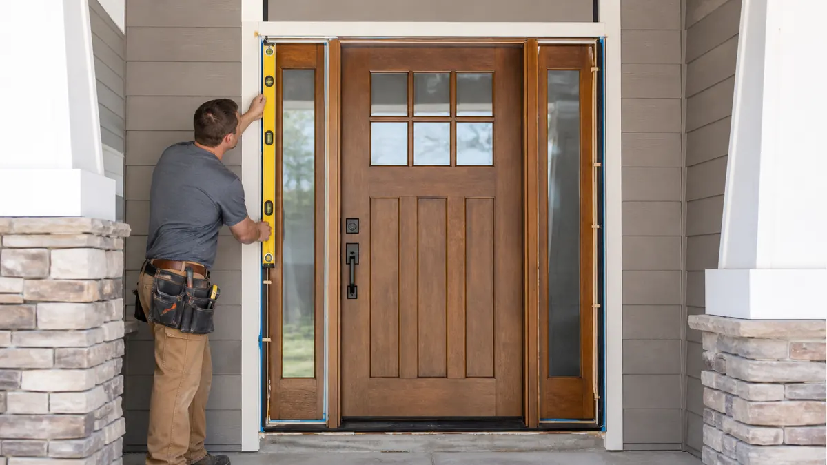 Installer checking a fiberglass exterior entry door and sidelights for level