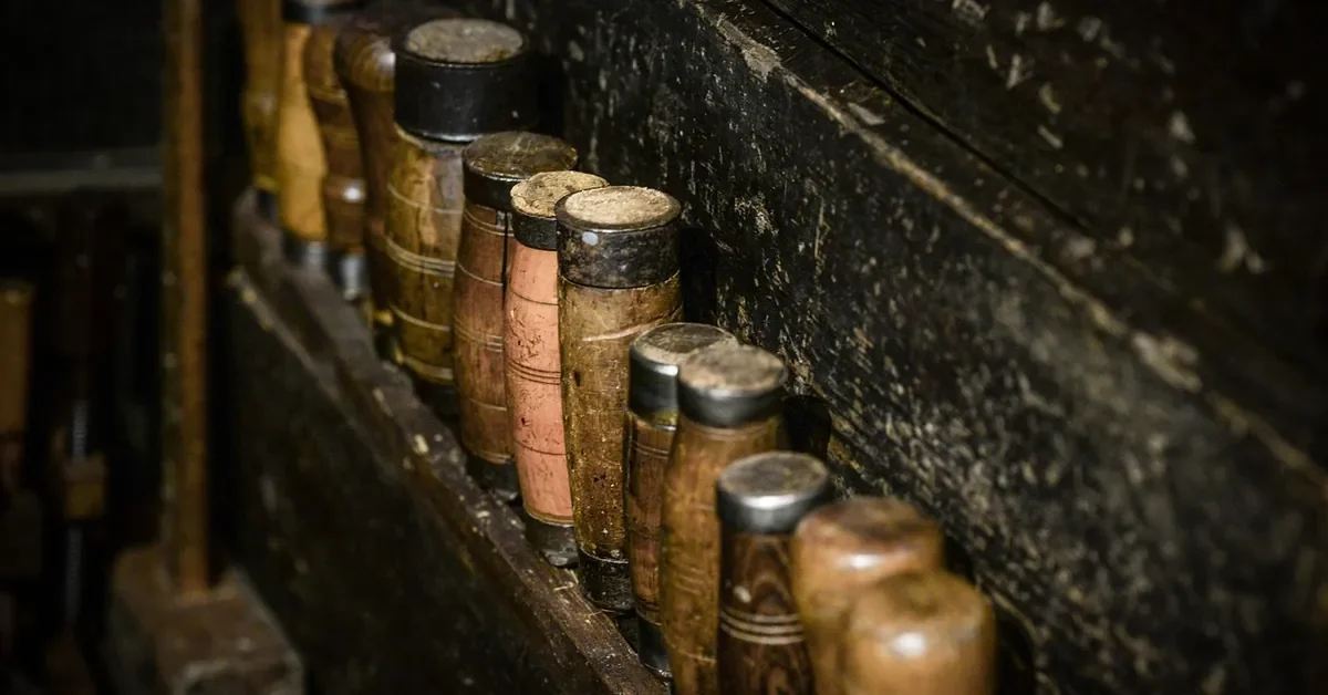 Row of wooden mortise chisel handles on a workshop tool rack