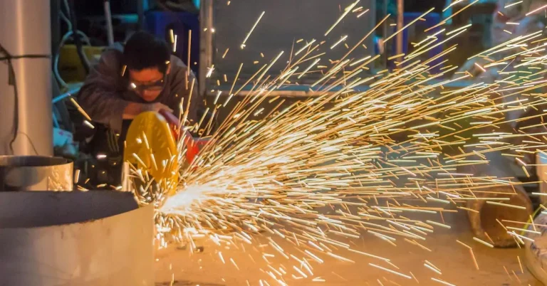 Worker cutting steel with a power saw, sparks flying from the blade