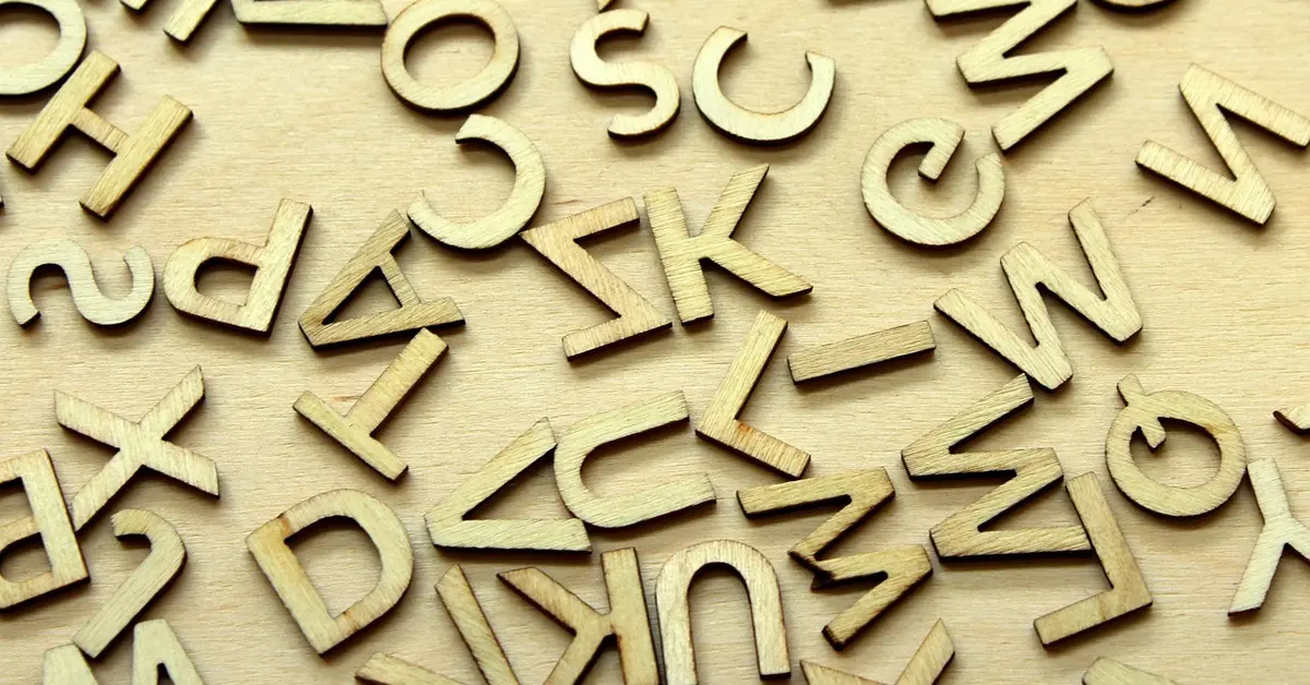 Wooden letters cut from plywood with a jigsaw, scattered on a wood surface