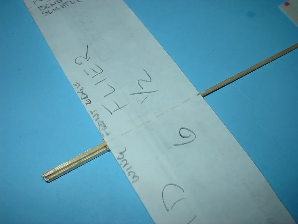 Close-up of a hardwood-to-plywood joint with clamps and brads reinforcing the bond