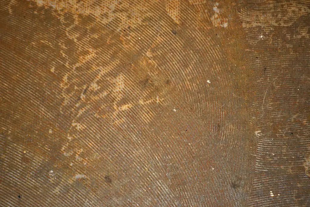 Hands lift a wood sample from carpet to inspect a removable adhesive strip