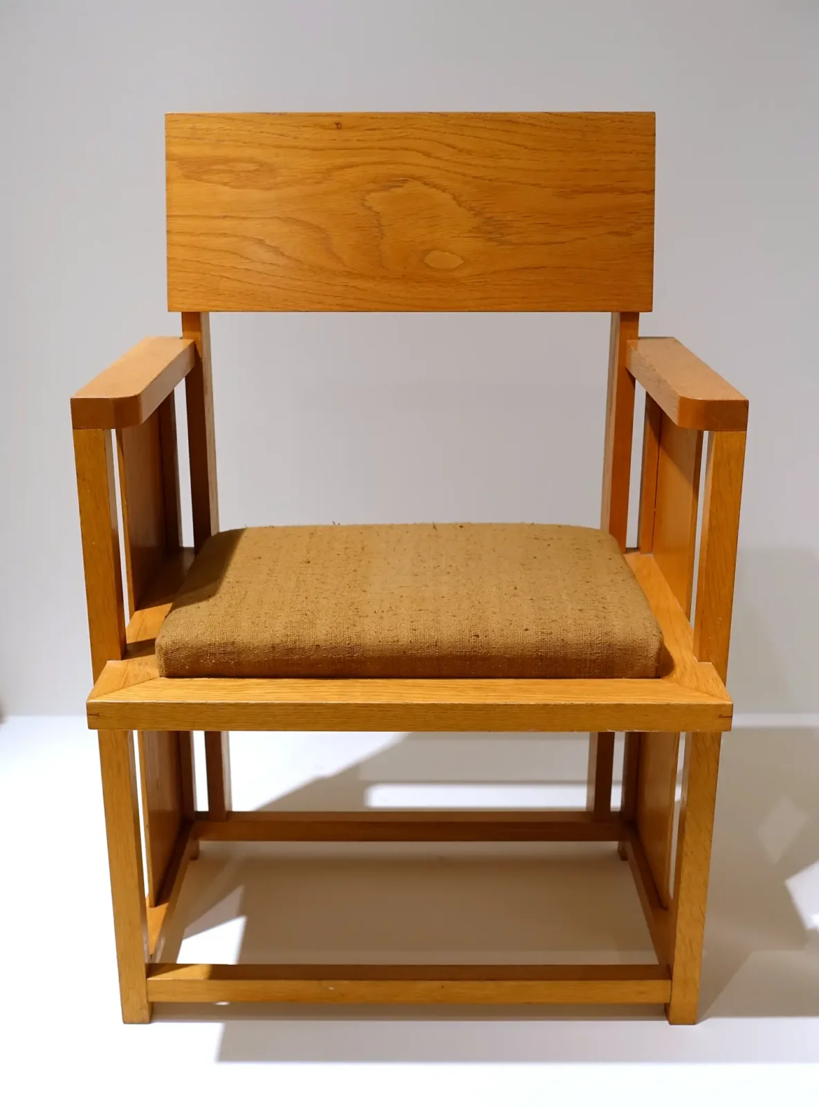 Hands pressing a wood trim piece onto fabric with adhesive, clamps and a staple gun nearby.
