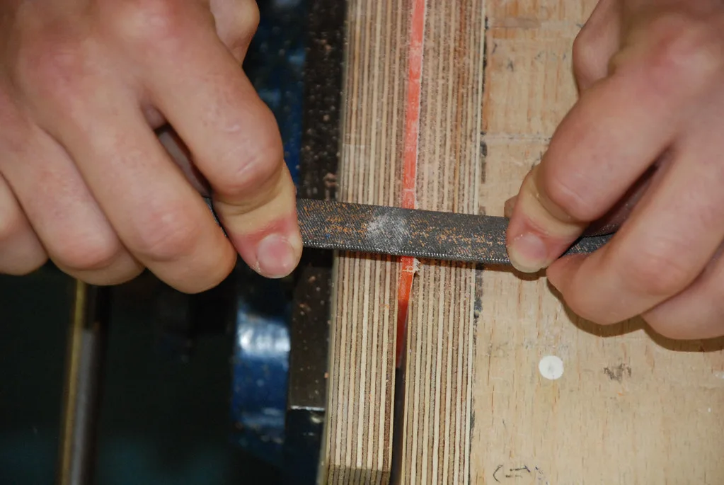 Gloved hand cleaning glue squeeze-out from a clamped cedar furniture joint