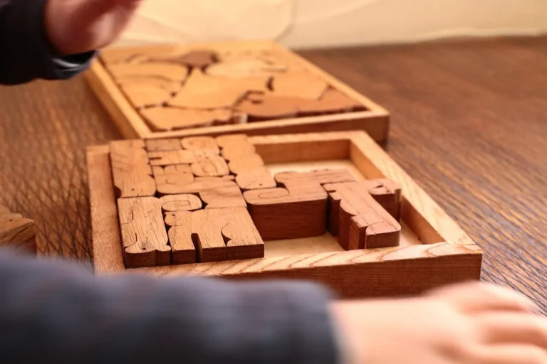 Craftsperson aligning glued wooden puzzle pieces on a workbench
