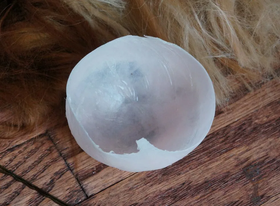 Wood glue on a wooden panel being gently scraped with a plastic tool in natural light