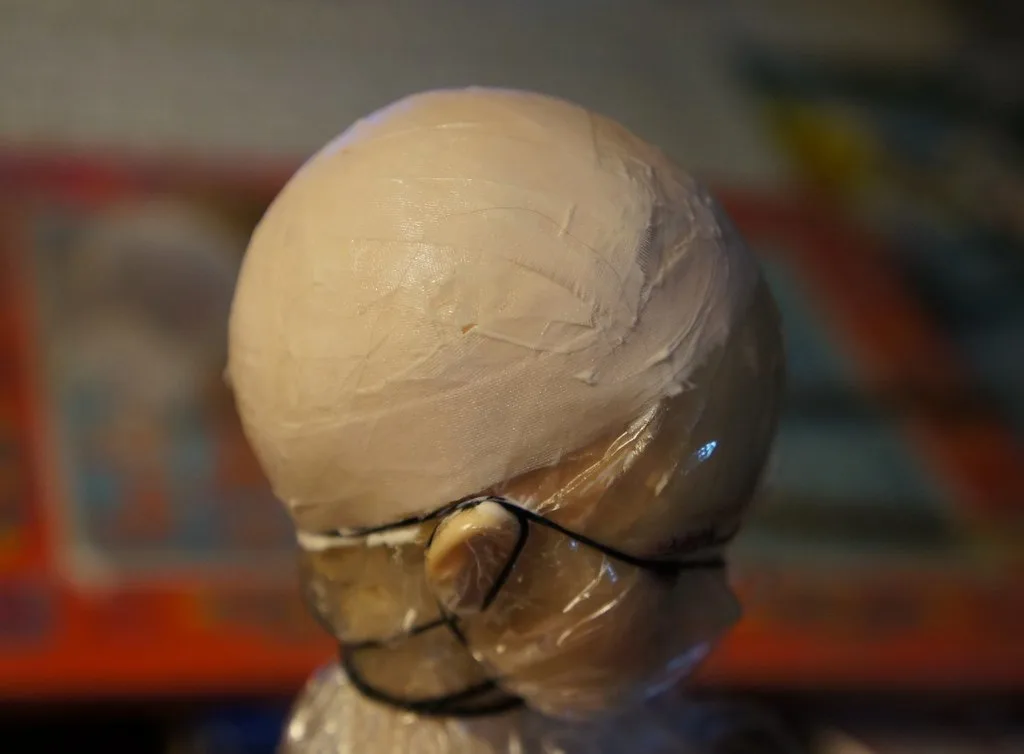 Close-up of dried wood glue being lifted from a varnished wood surface with a plastic scraper