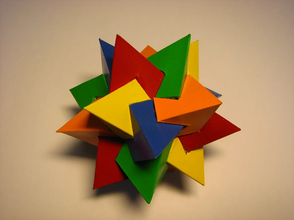 Close-up of glue bonding balsa wood to layered cardboard with a small clamp