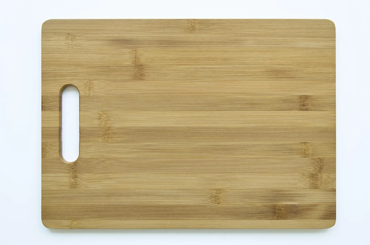 Three bamboo cutting boards on a kitchen counter with vegetables and a knife.